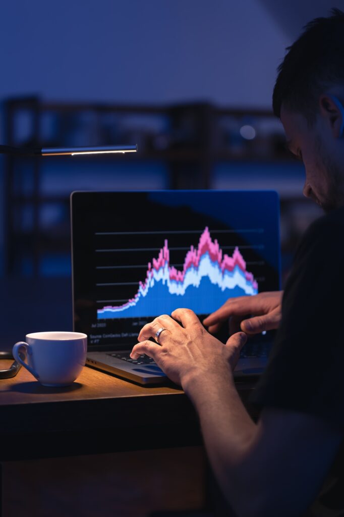 Broker looking at laptop analyzing stock market invest trading stocks graph.